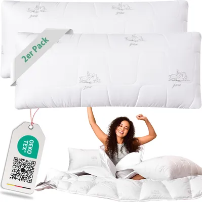 A woman is stretching happily in bed with pillows and a comforter.