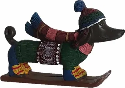 A decorative figurine of a dachshund dog dressed for winter and riding on skis.