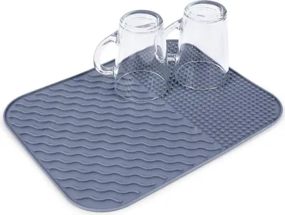 Two clear glasses are placed on a gray drying mat.