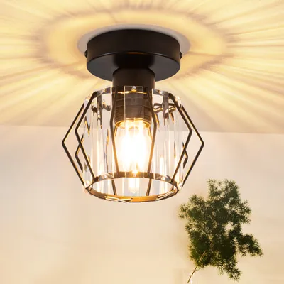 A close-up shot of a modern ceiling light fixture with a black metal frame and crystal accents, mounted on a white ceiling.