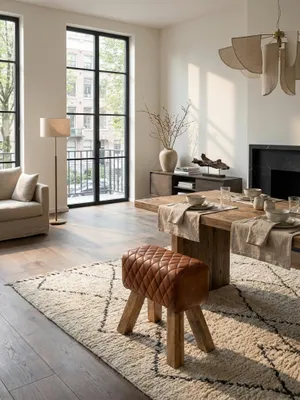 Eleganter Sitzhocker aus braunem Echtleder und Massivholz als stilvoller Akzent in einem modernen Wohnzimmer mit hellem Teppich und Holzboden._#sku_SAFWL6.092#
