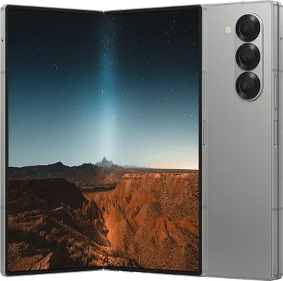 A silver foldable smartphone displaying a landscape image of a canyon under a starry sky.