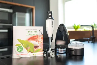 Der Stabmixer Unold ESGE-Zauberstab® Petticoat Edition mit Aufsätzen steht neben dem Koch- und Zaube
