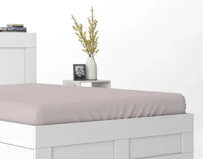 A close-up view of a white bed frame with a pink fitted sheet.