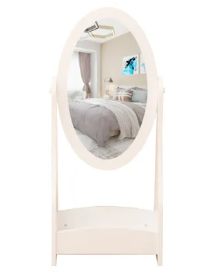 A full-length oval mirror with a white frame and a shelf at the bottom, shown against a white background. The mirror reflects a bedroom scene.