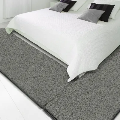 A bedroom setting with a bed and rugs.