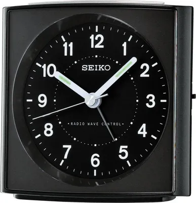 A close-up of a black Seiko alarm clock with a black face and white numbers and hands.