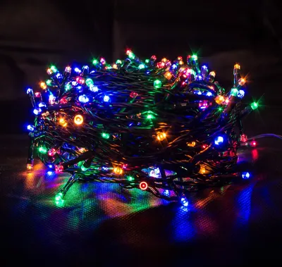 A close-up view of a tangled string of multicolor LED lights against a dark background.