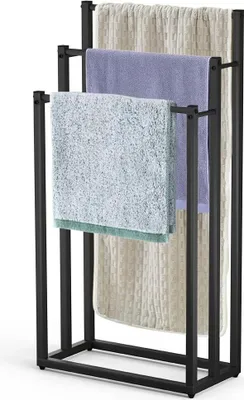A black metal towel rack with three bars, holding three different colored towels.