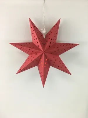 A red star-shaped lantern hangs against a white wall.