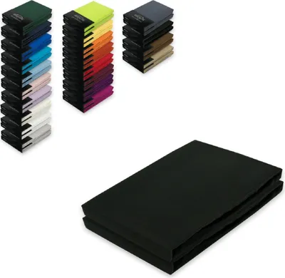 A stack of black jersey fitted sheets is shown in the foreground, with several stacks of fitted sheets in various colors in the background.