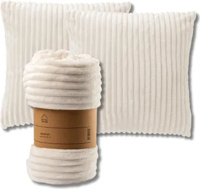 A set of white decorative pillows and a rolled-up blanket with a brown cardboard band.