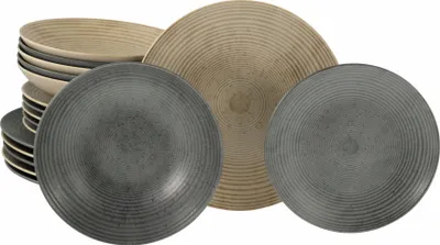 A set of stoneware plates and bowls with a ribbed texture, arranged in a stack and partially spread out.