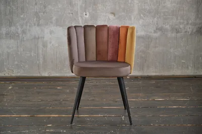 A chair with a multi-colored backrest and a brown seat, standing on a wooden floor in front of a concrete wall.
