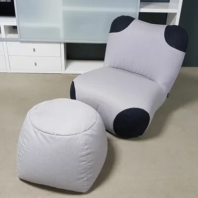 A gray and black beanbag chair and ottoman are shown on a light gray floor in front of a white entertainment center.