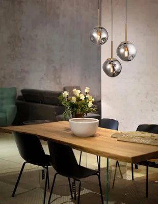 A dining room setting with a wooden table, chairs, and pendant lights.