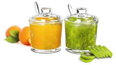 Two glass jars filled with jam, one orange and one green, are displayed next to fresh fruit.