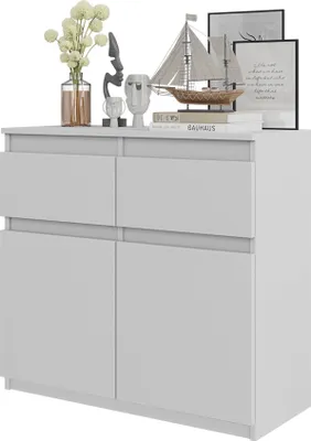 A white sideboard with decorative items on top, including a vase of flowers, sculptures, and books.