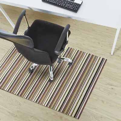 An office chair on a striped rug in front of a desk.
