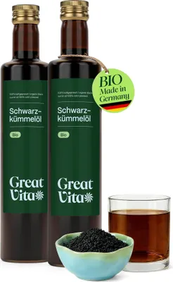 Two bottles of black cumin seed oil, a small bowl of black cumin seeds, and a glass of the oil.
