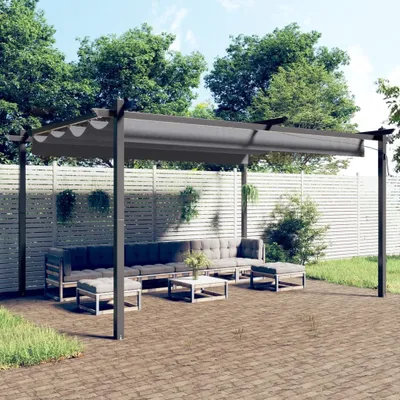 A modern outdoor lounge area with a grey pergola, sofa, coffee table, and ottomans on a brick patio, surrounded by greenery and a white slatted fence.