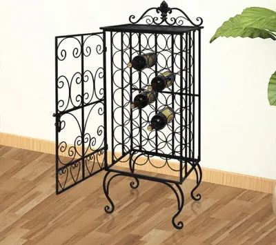 A black metal wine rack with an open door, holding several wine bottles, is placed on a wooden floor next to a wall. A large green leaf plant is visible on the right side.