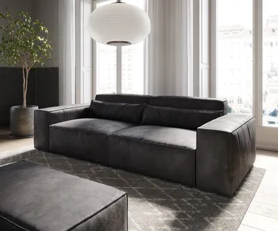 A modern living room with a large sofa and ottoman.