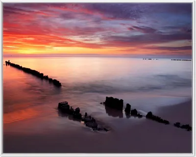 Produktbild von Wallario Wandbild Sandstrand im Sonnenuntergang - Roter Himmel, Größe: 40,30 x 50,30 cm, Poster mit weißem Aluminiumrahmen