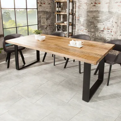 A dining table in a room with industrial-style brick walls and a large window.
