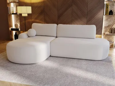 A modern white sectional sofa is placed on a light gray rug in a living room with a wood-paneled wall.