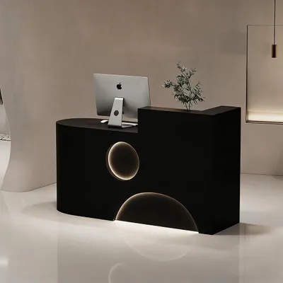 A black reception desk with a computer and a plant on it, in a modern interior.