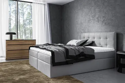 A modern bedroom with a boxspring bed, dresser, and large window.