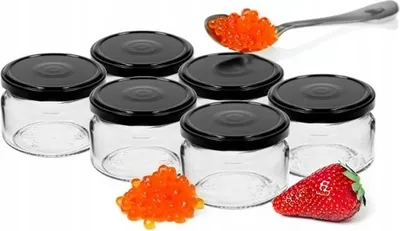 Six small glass jars with black lids, a spoonful of red caviar, and a pile of red caviar with a strawberry.