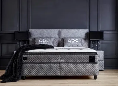 A luxurious bedroom setting featuring a large bed with pillows and a blanket, flanked by nightstands with lamps.