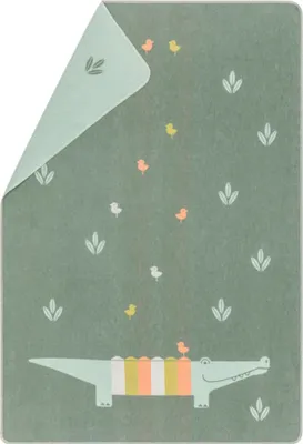 A flat lay of a baby blanket with a green background and a cartoon alligator and birds design.