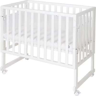 A white wooden crib with a mattress and mesh sides, shown from a slightly elevated side angle against a white background.