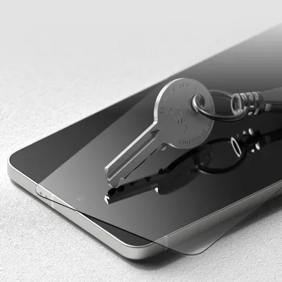 A key rests on a smartphone screen protector, which is placed on a smartphone.