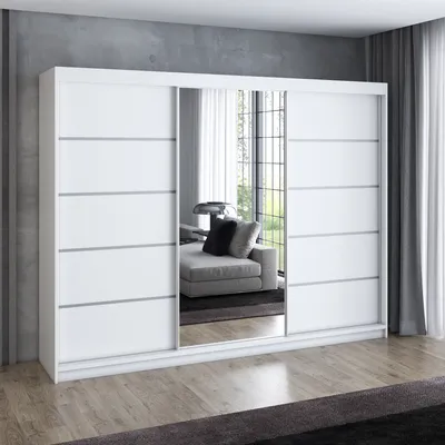 A white sliding door wardrobe with mirrored doors, reflecting a living room interior with a sofa and a window.
