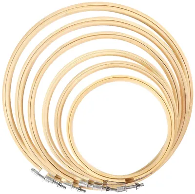 A set of wooden embroidery hoops of various sizes, stacked on a white background.