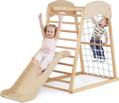 Two children playing on a wooden indoor climbing frame with a slide and net.