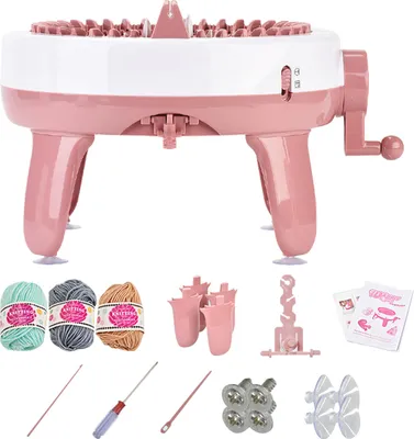 A pink and white knitting machine with various accessories laid out below it.