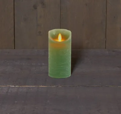 A green LED candle with a flickering flame sits on a dark wooden surface against a dark wooden plank background.