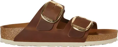 A side view of a brown Birkenstock Arizona sandal with large gold buckles.