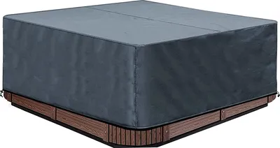 A gray cover is placed over a square hot tub with a wooden base.