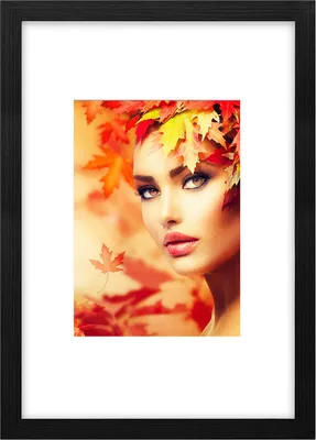 A woman's face is adorned with autumn leaves, with a blurred background of more leaves.