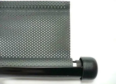 A close-up of a black roller blind with a perforated pattern, attached to a black rod with a black end cap.