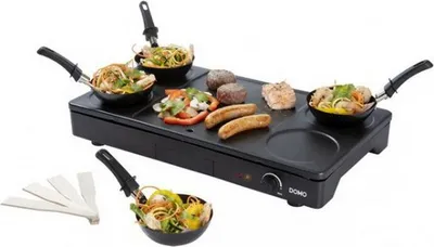 A black raclette grill with food items on it, set against a white background.