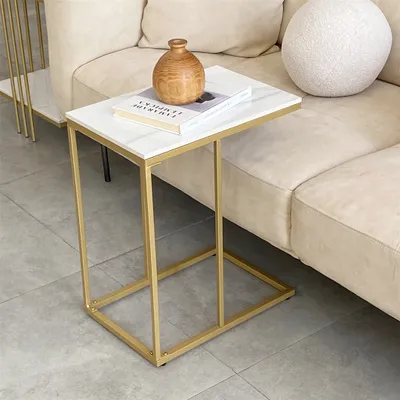 A side table with a marble-look top and gold metal frame sits next to a beige sofa.