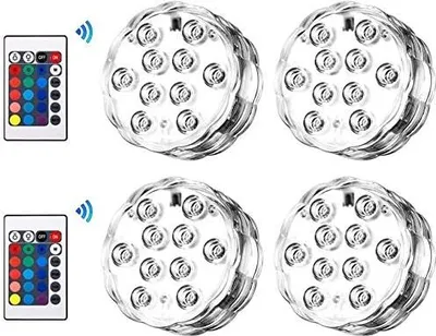 A product shot of multiple submersible LED lights and two remote controls, arranged on a white background.