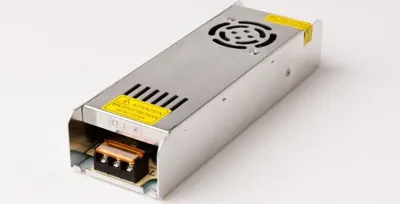 A silver power supply unit with ventilation grilles and warning labels, placed on a white background.